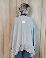 Ruana tejida de algodón con diseño abierto, terminaciones con volados y textura acanalada en los bordes.