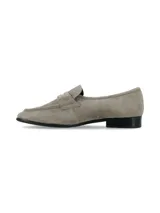 Mocasines de gamuza en color gris taupe, con diseño clásico de antifaz en el empeine y detalle de placa metálica dorada. Tacón bajo y suela negra.