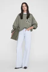 Buzo oversize color verde militar, con cuello redondo, mangas largas de hombros caídos y monograma estampado en el pecho con efecto desgastado.