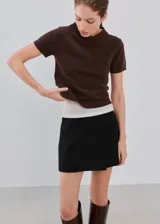 Minifalda negra de corte cruzado con diseño tipo short pollera, confeccionada en mezcla de poliéster, viscosa y elastano.