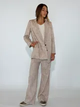 Blazer de lino y algodón en tono beige con textura a rayas verticales sutiles. Presenta solapas clásicas, un solo botón frontal marrón y un corte ligeramente holgado. Los bordes de las mangas y el ruedo tienen un acabado deshilachado.