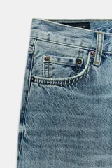 Jeans de tiro medio con corte slim y largo completo. Presentan diseño de cinco bolsillos, cierre frontal con cremallera y botón, efecto lavado y detalle de rotura en la parte delantera con bajo sin costura.