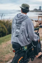 Hoodie de color gris con efecto lavado, corte oversize y capucha. Presenta un estampado gráfico en la espalda con motivos playeros, palmeras, flores y la inscripción Glassy Waves Club.