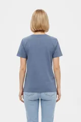 Remera de manga corta color azul con estampa frontal oscura de una ballena decorada con motivos florales.