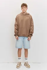 Canguro marrón con capucha, bolsillo frontal tipo kango y diseño oversize de corte relajado con mangas largas.