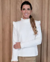 Polera de manga larga color blanco, con cuello alto, volados en los hombros y en los puños.