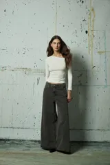 Jean de corte wide leg en color gris lavado, con diseño de aberturas laterales decoradas con tachas metálicas a lo largo de toda la pierna.