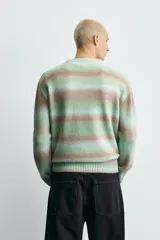 Jersey de punto con ajuste relajado, cuello redondo y manga larga. Presenta un diseño de rayas horizontales difuminadas en tonos verde agua y marrón, con acabados en rib en cuello, puños y ruedo.