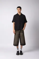 Camisa de manga corta confeccionada en lino, con cuello clásico y cierre frontal de botones. Presenta un corte relajado y una textura natural característica del tejido.