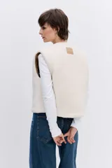 Chaleco reversible de diseño acolchado con costuras en rombos, color tostado con interior de corderito blanco. Presenta cierre frontal con botones, cuello redondo y bolsillos delanteros.