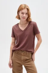 Remera marrón de manga corta con escote en V y diseño al cuerpo. Presenta un delicado detalle de tachas metálicas en forma de estampa en el hombro izquierdo.