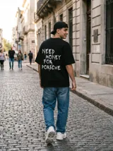 Remera negra de algodón con corte oversize y estampado blanco en la espalda con la frase "Need Money For Porsche".