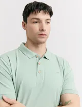 Chomba de piqué color verde con cuello clásico, tapeta de dos botones de madera y mangas cortas con puños acanalados.