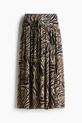 Pollera maxi de tiro alto confeccionada en gasa con estampado de cebra en tonos beige y negro. Cuenta con cintura ancha y costura fruncida en diagonal.