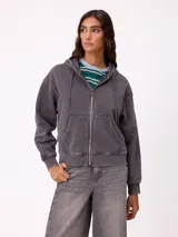 Canguro con cierre frontal y capucha, color gris con efecto desgastado. Presenta bolsillos laterales y logo bordado en el pecho.