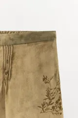 Shorts de tiro bajo con cintura elástica y detalle de pliegues en el delantero. Presenta un diseño estampado con motivos florales en tonos tierra.