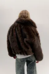 Campera bomber de piel sintética en color marrón chocolate, con diseño de cuello alto, cierre frontal y puños elásticos en color negro.