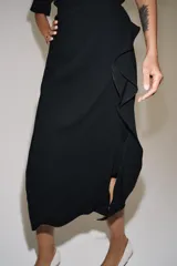 Falda midi de tiro medio negra confeccionada en hilatura con mezcla de viscosa, con detalle de pliegues y volante frontal, y bajo acabado en abertura.