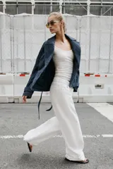 Cazadora de piel gamuzada color azul marino, con cuello de solapas, cierre cruzado con botones forrados y cinturón ajustable del mismo tejido. Presenta mangas largas con trabillas en los puños.