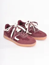 Championes de estilo urbano en color bordó, confeccionados en gamuza con detalles en cuero blanco. Presentan cordones gruesos con estampado de lunares y suela de goma color caramelo.