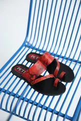 Sandalias rojas con estampado de piel de serpiente, con tira entre los dedos y suela plana.