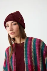 Gorro tipo beanie de punto acanalado en color bordo, con diseño de doblez en el borde y pequeña etiqueta lateral decorativa.