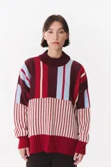 Buzo de tejido de punto con diseño de paneles rayados en combinación de colores bordó, celeste y crema. Presenta cuello alto, corte oversize y terminaciones en rib en puños y ruedo.