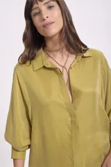 Camisa de manga larga color verde oliva, con cuello solapa y botones frontales. Corte holgado.