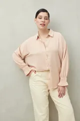 Camisa negra de manga larga con cuello clásico y botones frontales. El tejido presenta una textura arrugada o plisada, y los puños tienen un frunce elástico.