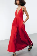Vestido largo rojo de Zara Woman Collection confeccionado en hilatura con mezcla de algodón. Escote pico y tirantes finos cruzados en la espalda ajustable con lazadas. Tiene bolsillos laterales, detalle de pliegues en la cintura y cierre en la espalda con cremallera oculta en la costura.