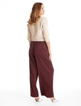Pantalón tipo palazzo de corte ancho y fluido, confeccionado en tejido sastrero. Presenta tiro alto con doble abotonadura frontal, pinzas decorativas y cintura elástica en la parte posterior. Incluye bolsillos laterales funcionales.