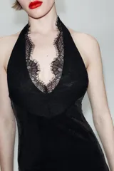 Vestido corto de lentejuelas negras con cuello halter y escote en pico profundo. Presenta detalles de encaje en el escote y espalda descubierta con cierre de botones en el cuello.