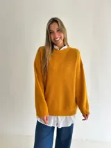 Sweater de punto con textura tipo waffle, color mostaza, de corte holgado, cuello redondo y mangas largas con puños acanalados.