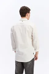Camisa de manga larga color gris oscuro, confeccionada en tejido liviano con textura sutil, cuello tradicional y cierre frontal de botones.