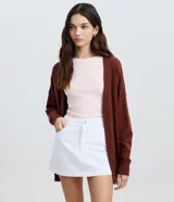Cardigan de punto color marrón, de corte largo, mangas largas con sisa desplazada y frente abierto sin botones.
