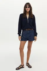 Sweater de punto azul marino de calce relajado, con mangas largas abullonadas, cuello polo y cierre frontal con botones. Presenta detalles en contratono blanco en la aberturas del cuello y puños.