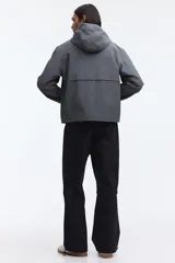 Campera rompevientos de nylon repelente al agua, con capucha ajustable, cierre frontal completo, bolsillos laterales y puños elásticos.