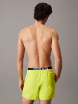 Bañador corto de hombre color amarillo flúor, con cintura elástica negra con logo Calvin Klein en blanco.
