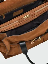 Bolso tote de gamuza color marrón, con diseño estructurado, cierre de hebilla metálica frontal y correas de hombro de cuero negro.