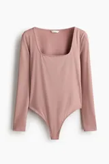 Body de manga larga confeccionado en punto elástico color rosado, con diseño colaless, escote cuadrado y cierre con botones a presión en la parte inferior.