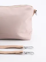 Bandolera rosada con cierre superior y correa ajustable. Cuenta con un detalle colgante de cordones coloridos en el lateral.