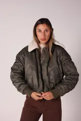 Campera bomber verde militar con cuello de corderito desmontable, cierre frontal y puños y ruedo elastizados.