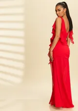 Vestido largo de fiesta color rojo, con escote en V, hombros con detalle de volados y tajo lateral profundo. Presenta un diseño fruncido en la cintura con un aplique floral decorativo.