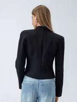 Chaqueta estilo militar color negro, con cuello mao y cierre frontal decorado con cordones trenzados y botones metálicos dorados.