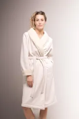 Bata larga color crema confeccionada en pana, forrada en corderito y con puntilla de algodón en solapa y puños. Tiene bolsillos laterales y lazo de pana para ajustar en la cintura.