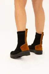 Bota de caña media de cuero color negro con detalles en marrón y suela track.