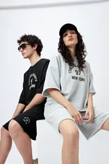 Bermuda negra de algodón y poliéster, de corte relajado y tiro medio, con cordón ajustable en la cintura y estampado con inspiración college.