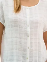Blusa de corte fluido confeccionada en algodón con tejido texturizado de patrón a cuadros. Presenta mangas cortas caídas, escote redondo y cierre frontal con botones.