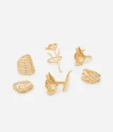 Set de seis anillos de metal con baño dorado, que presentan diversos diseños, formas orgánicas y texturas variadas.