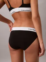 Bombacha clásica tipo bikini de Calvin Klein, color negro, confeccionada en mezcla de algodón, modal y elastano. Presenta una pretina elástica distintiva con el logo de la marca en contraste y ofrece cobertura total en la espalda.